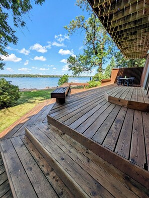 A wooden deck with a bench and table, overlooking a lake. - Hunting, Fishing, and ATV/Sled Trails at Lakefront home on Sturgeon Island! (Sturgeon Lake)