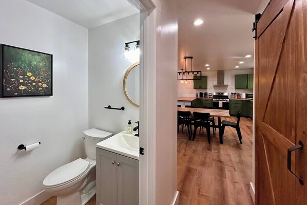 A modern bathroom with a toilet, sink, and a framed floral artwork on the wall. - Pickle/Basketball, Gym, Rockwall, Arcade, Hot Tub! (Lumpkin County)