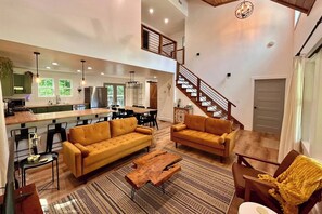 A spacious living area with a sofa, coffee table, and a staircase leading to an upper level. - Pickle/Basketball, Gym, Rockwall, Arcade, Hot Tub! (Lumpkin County)