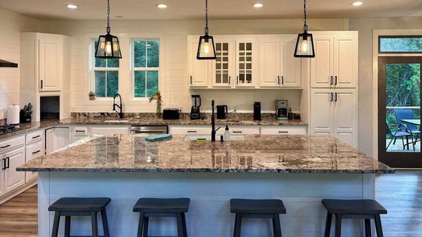 A modern kitchen with white cabinetry, granite countertops, and three hanging pendant lights. - Game & Movie Room, Minutes to Wine, Weddings &Town (Lumpkin County)