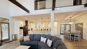 A spacious living room with a large sectional sofa, a dining area with a wooden table and chairs, and a modern kitchen with pendant lighting. - Game & Movie Room, Minutes to Wine, Weddings &Town (Lumpkin County)