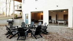 An outdoor seating area with Adirondack chairs and a table, a barbecue grill, and a ping pong table in a covered garage. - Game & Movie Room, Minutes to Wine, Weddings &Town (Lumpkin County)