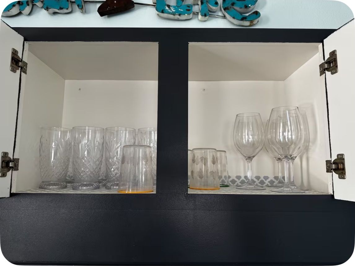 A cabinet with two shelves, each containing clear glassware.
