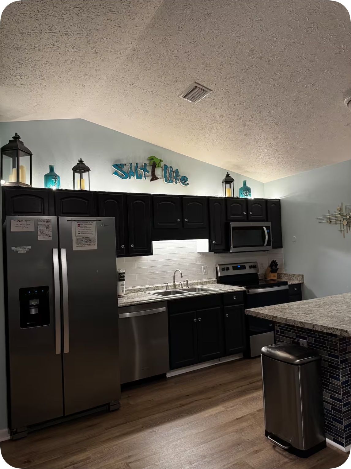A kitchen with dark cabinets, stainless steel appliances, and a backsplash.