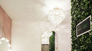 A reception area with a mirror, a chandelier, and a green wall with a sign.