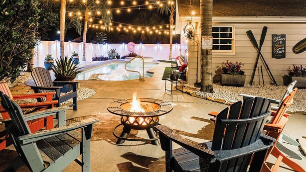 An outdoor patio area with seating, a fire pit, and string lights.