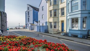Une rue bordée de bâtiments aux couleurs vives, avec un parterre de fleurs au premier plan.
