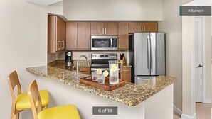 Una cocina con armarios de madera, un refrigerador de acero inoxidable, un microondas y una encimera de granito.