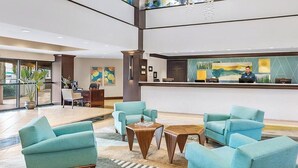 Un hall con sillones azul turquesa, un mostrador de recepción y un ventanal grande.