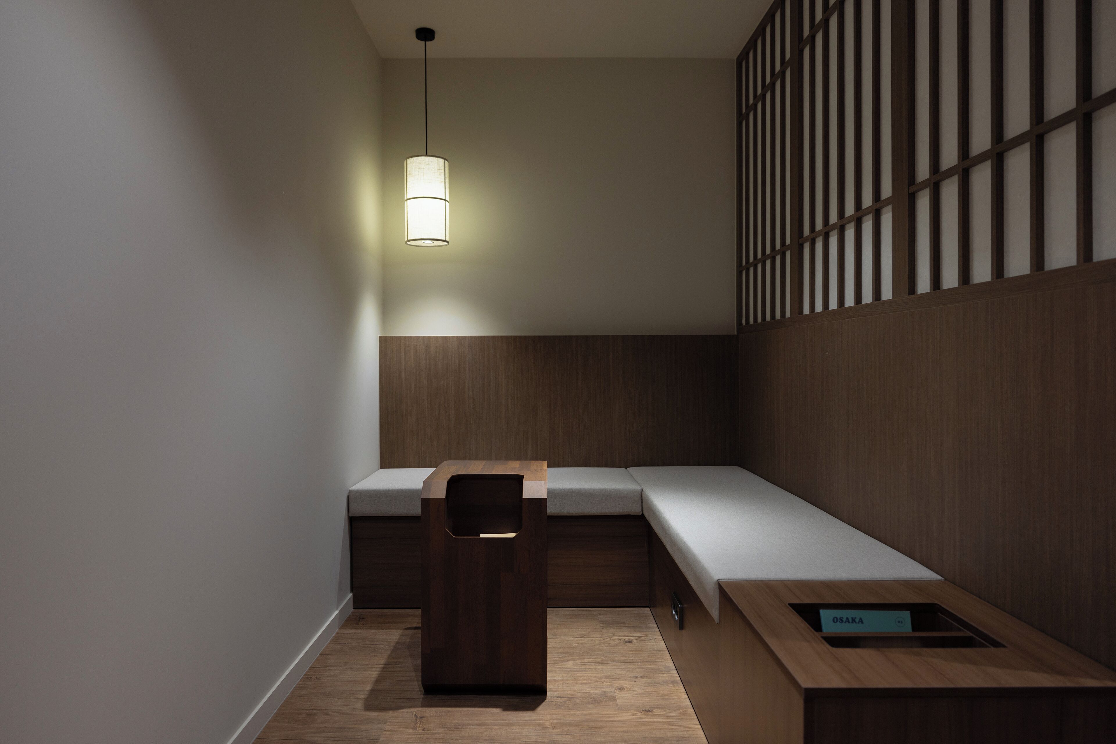 Una habitación moderna y minimalista con un banco de madera, una mesita y un aplique de pared.