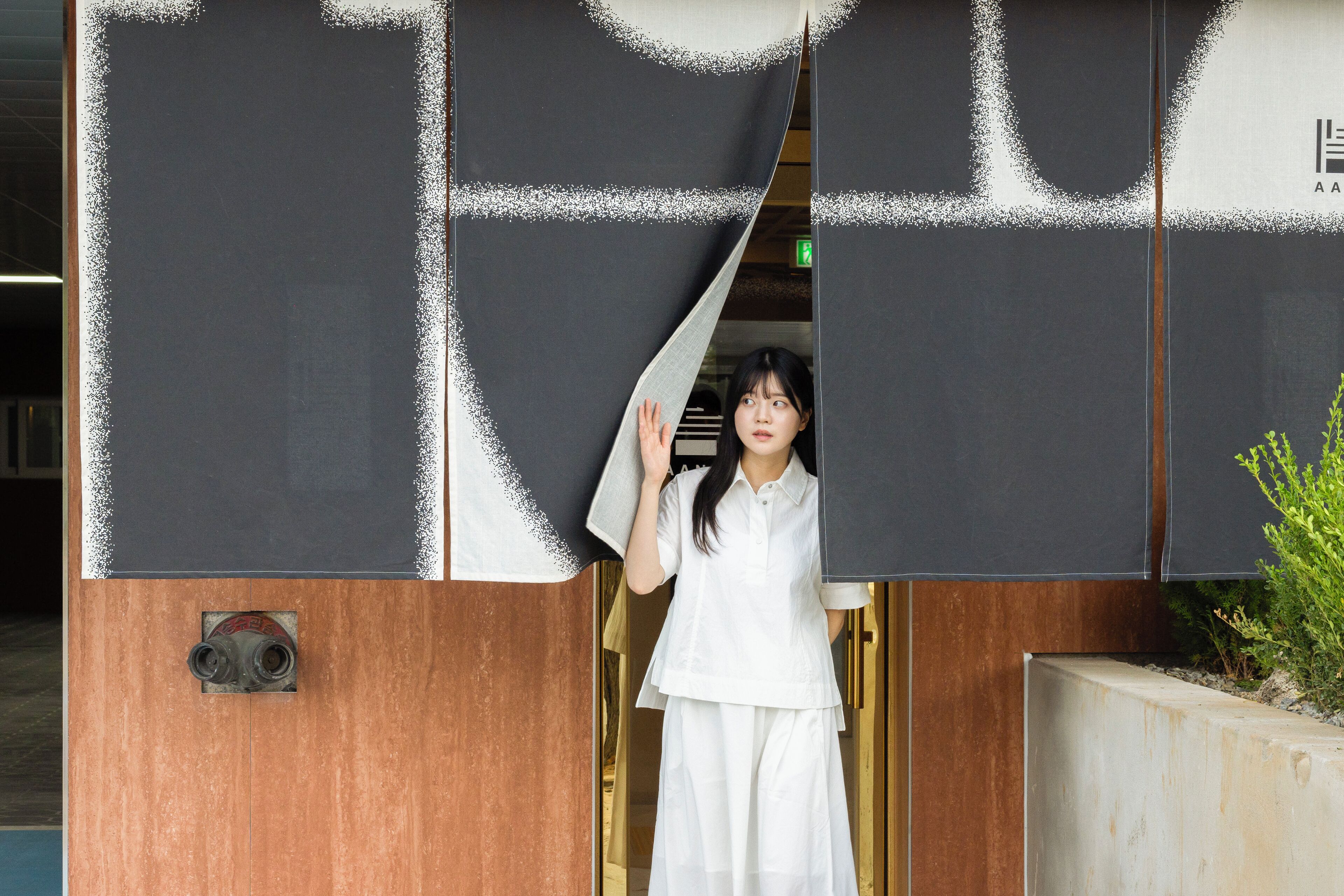 A person standing at the entrance of a building with a large, dark-colored door.