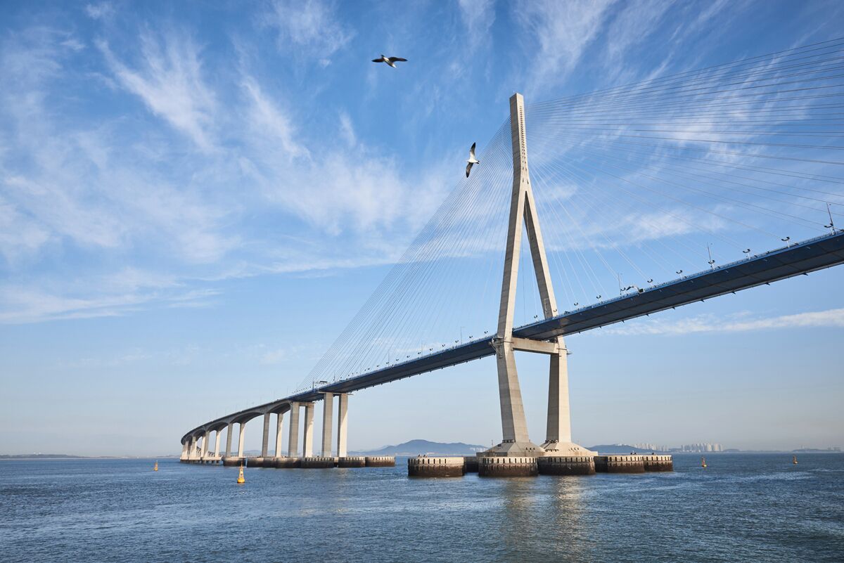 Un pont penjant gran amb diverses torres i cables que travessa una massa d'aigua.