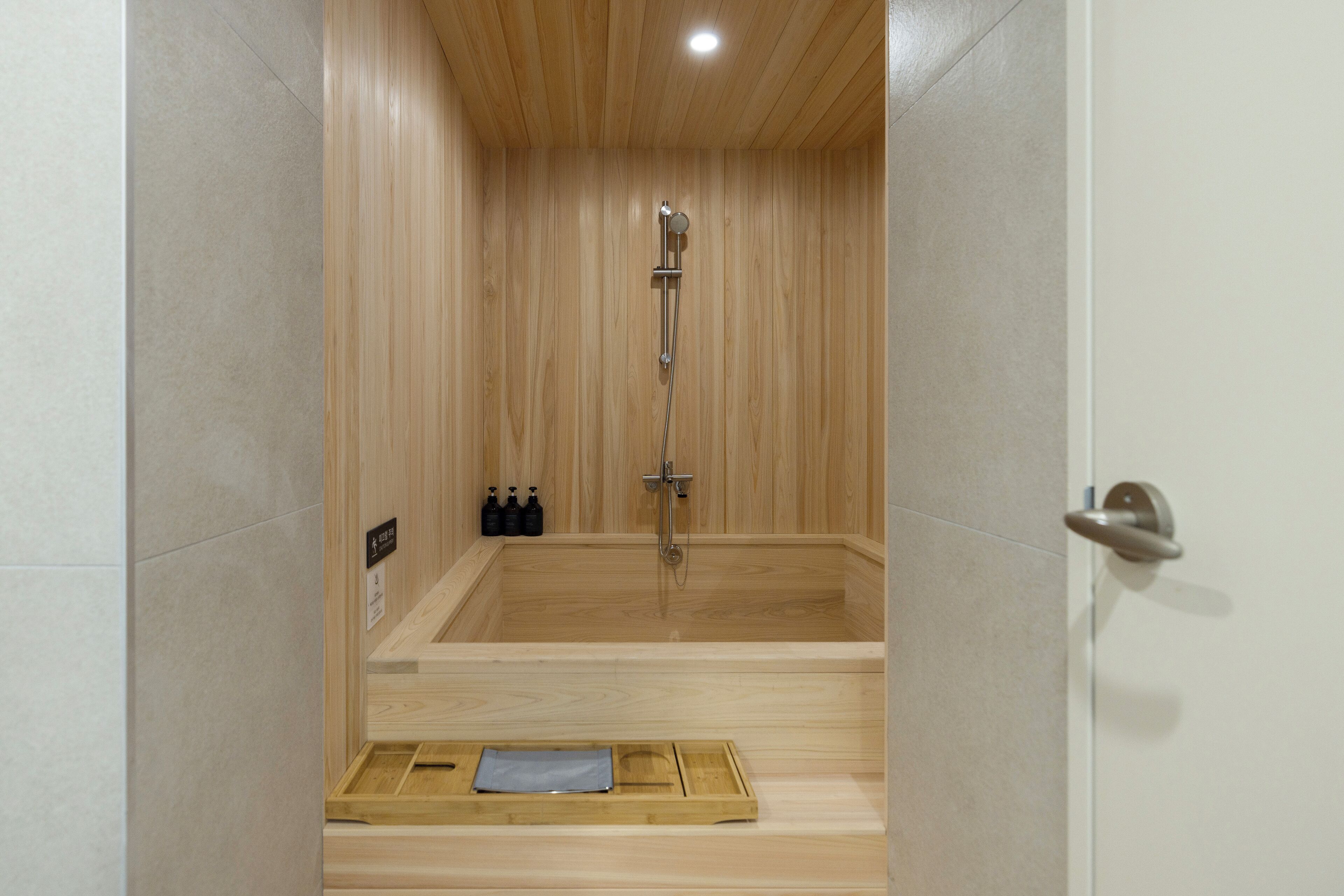 A wooden sauna with a showerhead, a towel rack, and a tray with a towel.