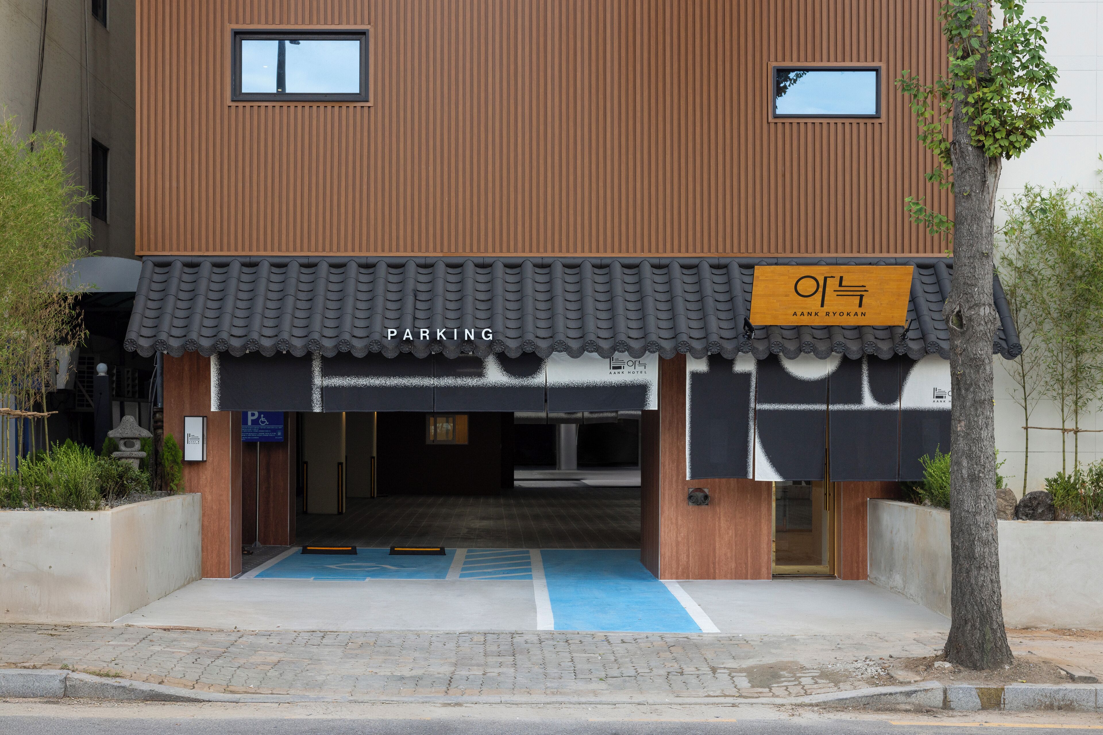 A hotel entrance with a parking sign, a blue parking space, and a wooden facade.