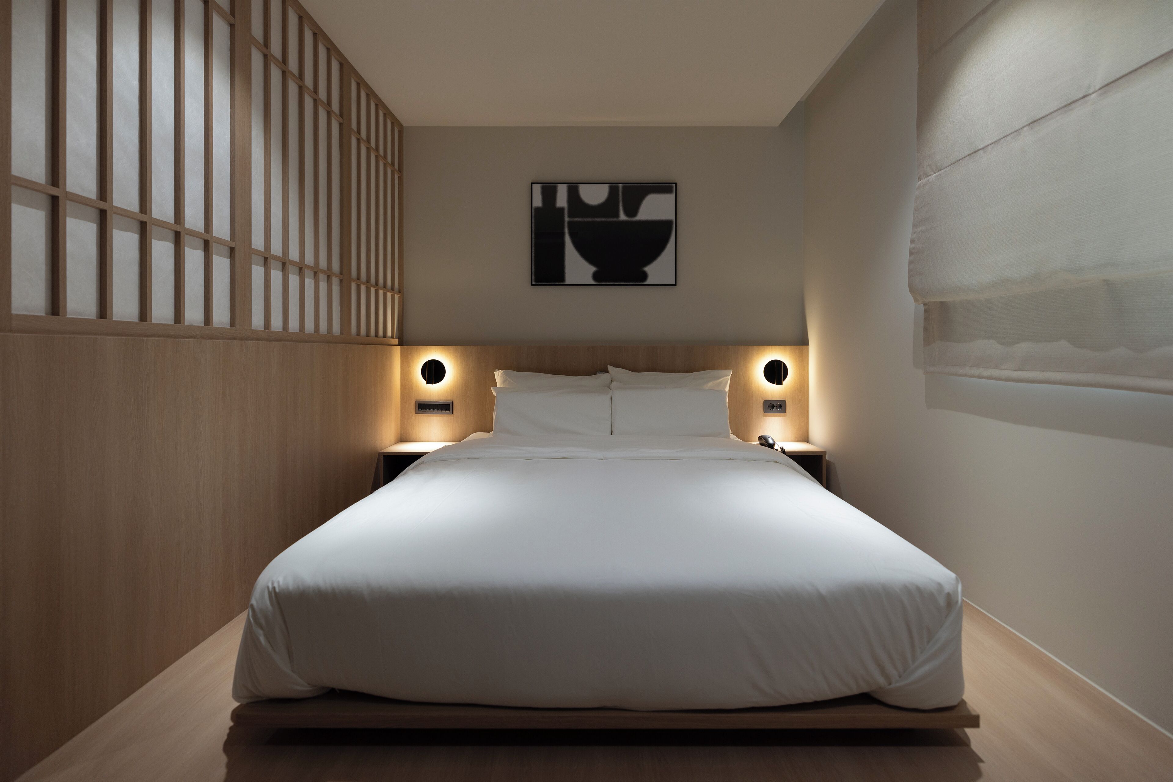 Un lit bien fait dans une chambre moderne avec un lambris en bois et une œuvre d’art accrochée au mur.