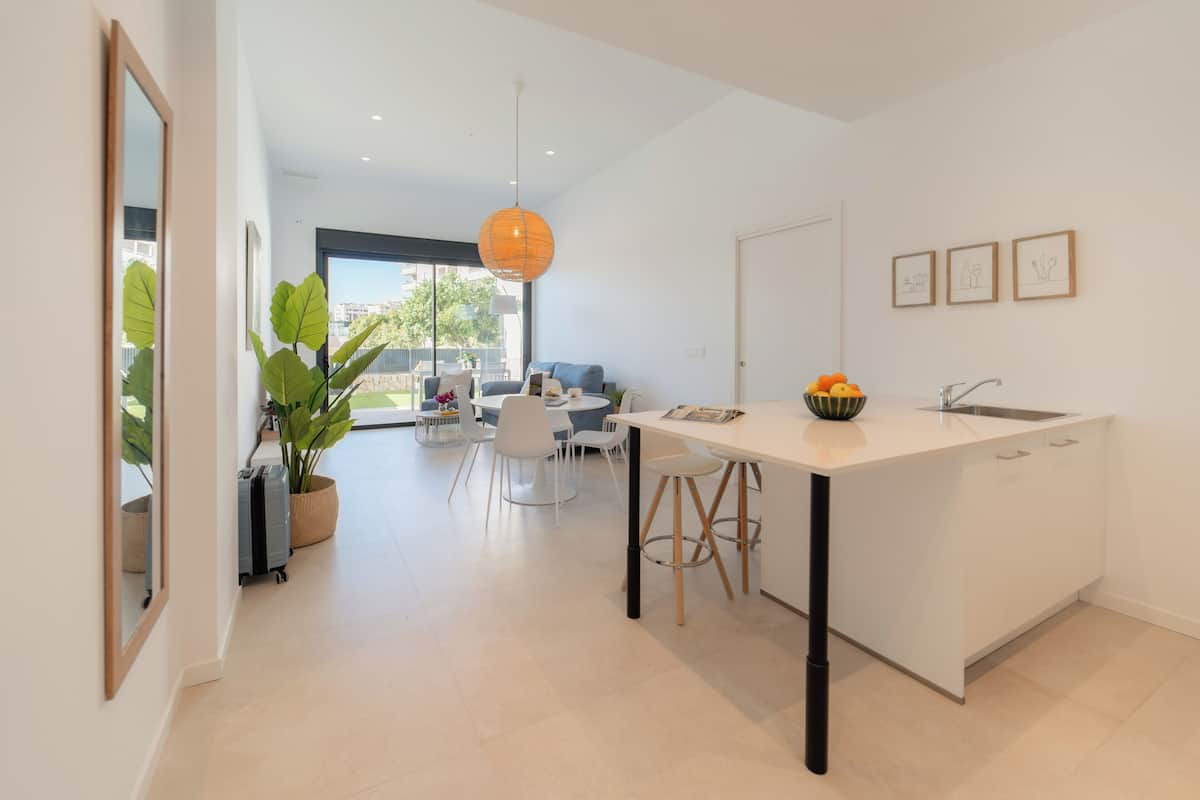 Una cocina moderna con una isla central, armarios blancos y un amplio ventanal que proporciona luz natural.