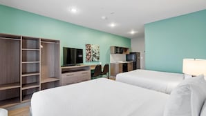 A hotel room with two beds, a desk, a TV, a microwave, and a wardrobe.