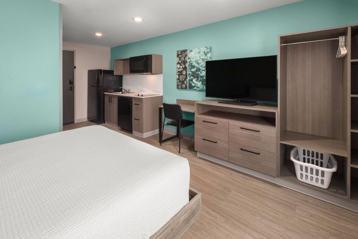 A bedroom with a bed, a desk, a chair, a television, and a wardrobe.