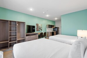 A hotel room with two beds, a desk, a TV, a microwave, and a wardrobe.