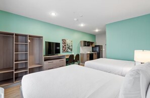Habitación de hotel con dos camas, un escritorio con silla, televisor, microondas y armario.