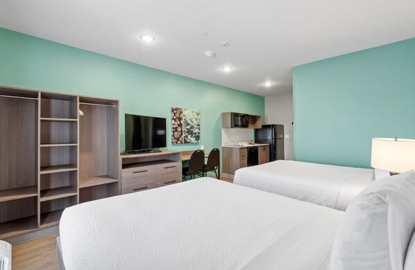 A hotel room with two beds, a desk with a chair, a TV, a microwave, and a wardrobe. - Echo Suites Extended Stay Wyndham Ft Worth Allianc (Keller)