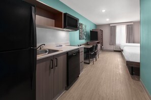 A compact hotel room with a kitchenette, a bed, a desk, and a television. - Echo Suites Extended Stay Wyndham Ft Worth Allianc (Keller)