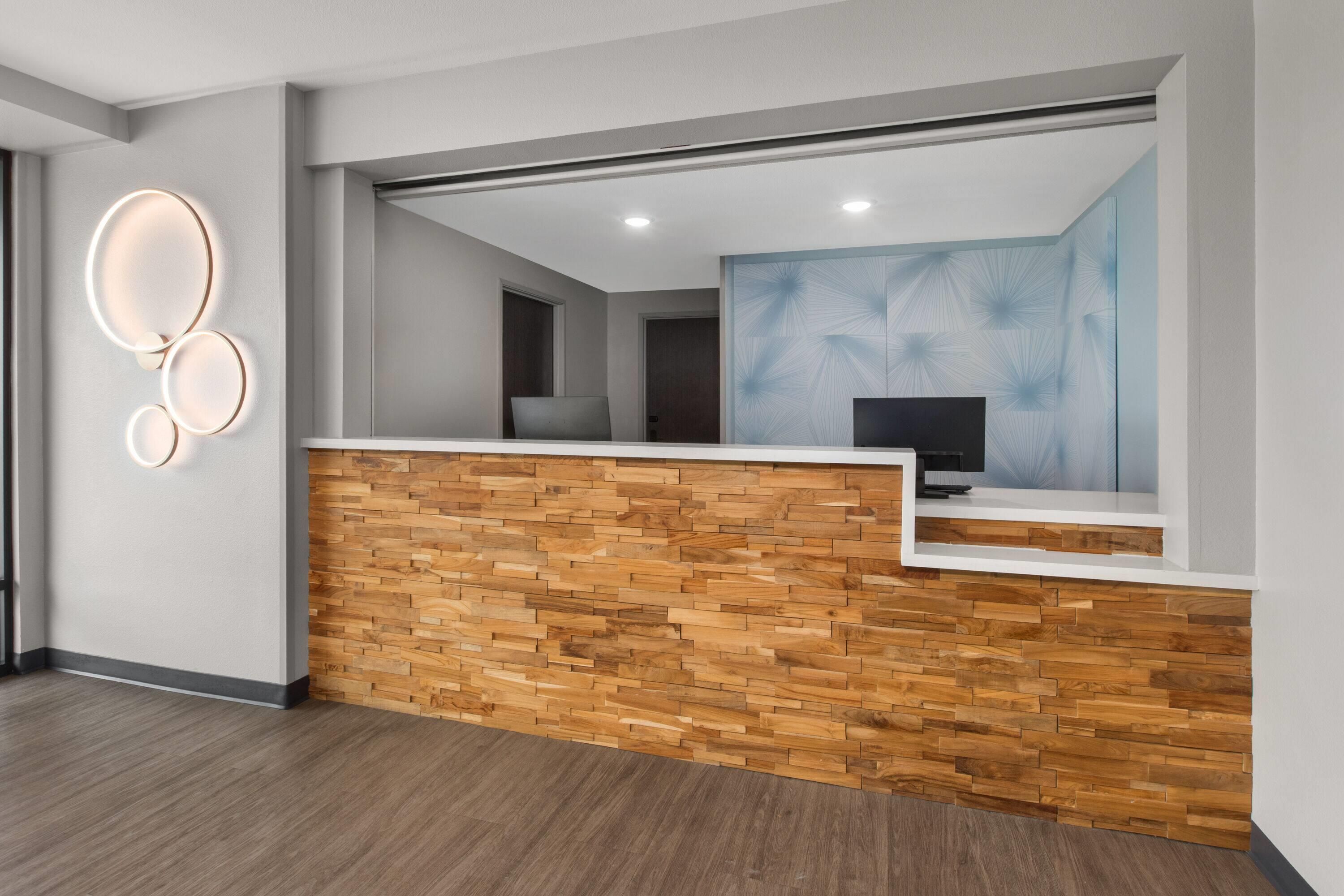 A reception area with a wooden reception desk, a wall-mounted light fixture, and a large abstract painting.