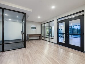 Un hall d’hôtel moderne avec des portes vitrées, un comptoir d’accueil et une vue sur l’extérieur.