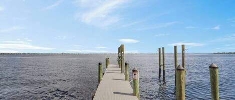 Un muelle de madera que se adentra en aguas tranquilas bajo un cielo despejado.