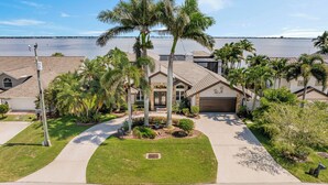 A residential area with houses, palm trees, and a body of water in the background. - VRCC Villa Dolphin House (Cape Coral)
