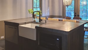 A modern kitchen with a large island, pendant lighting, and a view of the outdoors.