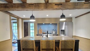 A spacious kitchen with a large island, wooden chairs, and pendant lighting.