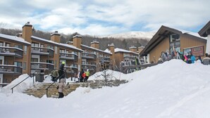 A ski resort with multi-story buildings, a rental shop, and a snow-covered staircase. - Okemo Mountain Lodge unit with Direct Access to Clocktower Base Area at Okemo (Ludlow)