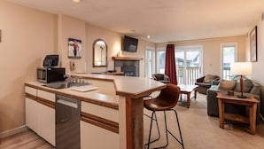 A compact living space with a kitchenette, a dining area, and a seating area with a view. - Okemo Mountain Lodge unit with Direct Access to Clocktower Base Area at Okemo (Ludlow)