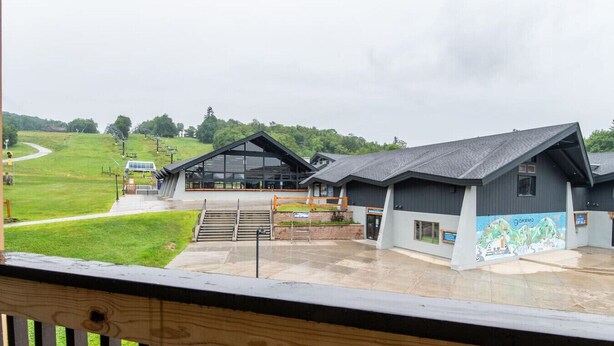 A building with a large glass facade, a ramp leading to the entrance, and a mural on the side. - Okemo Mountain Lodge unit with Direct Access to Clocktower Base Area at Okemo (Ludlow)