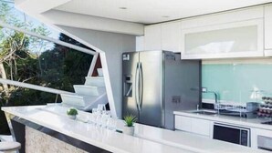 Una cocina moderna con una isla grande, taburetes de bar y un refrigerador.