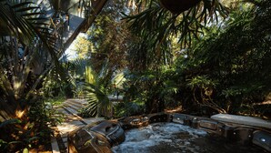 Un bain à remous entouré d’une végétation luxuriante et doté d’une terrasse en bois.