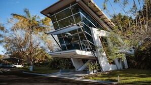 Un bâtiment moderne à la façade de verre, entouré d’arbres et sous un ciel dégagé.