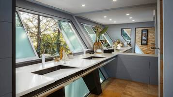 Een moderne keuken met grote ramen, een betegelde achterwand en uitzicht op de omgeving.
