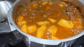 A pot of stew with potatoes and chunks of meat.