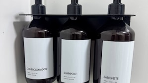 Three bottles of hair care products on a white tiled wall.
