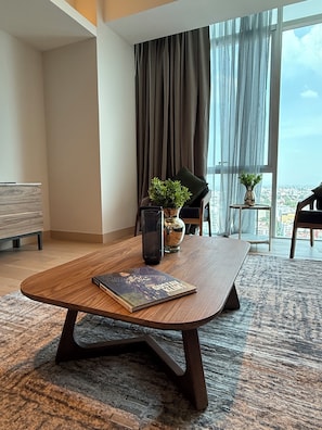 Une chambre dâhĂŽtel moderne avec une table en bois, une plante en pot, un vase et une vue sur la ville grĂące Ă de grandes fenĂȘtres.