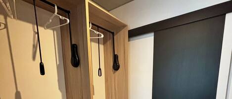 A modern bathroom with a wooden vanity, towel rack, and a black door.
