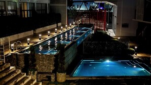 A swimming pool with steps leading up to it, surrounded by stone walls and illuminated by lights. - Modern Apartment with A/C - Steps from Ciudad Cayala & US Embassy (Ciudad de Guatemala)