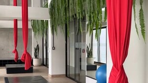 A spacious room with a wooden floor, red curtains, and hanging plants. - Modern Apartment with A/C - Steps from Ciudad Cayala & US Embassy (Ciudad de Guatemala)