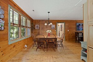 Un intérieur en bois comprenant une table à manger, des chaises et un lustre.