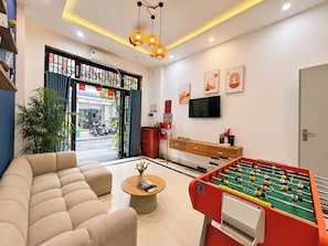 Una sala de estar moderna con un sofá, mesa de fútbol, televisor y una mesa de centro.