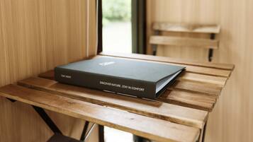 Un libro con el título "Discover Nature - Stay in Comfort" sobre una mesa de madera cerca de una ventana.