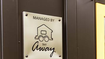 Une pancarte avec le texte « GÉRÉ PAR TINY Away » et un simple pictogramme représentant une maison et un train.