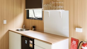 Cocina compacta con lavamanos, refrigerador y ventana con persiana.